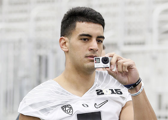 Oregon quarterback Marcus Mariota uses a small camera to film media representatives and others as he arrives for the team's media day session. Associated Press photo