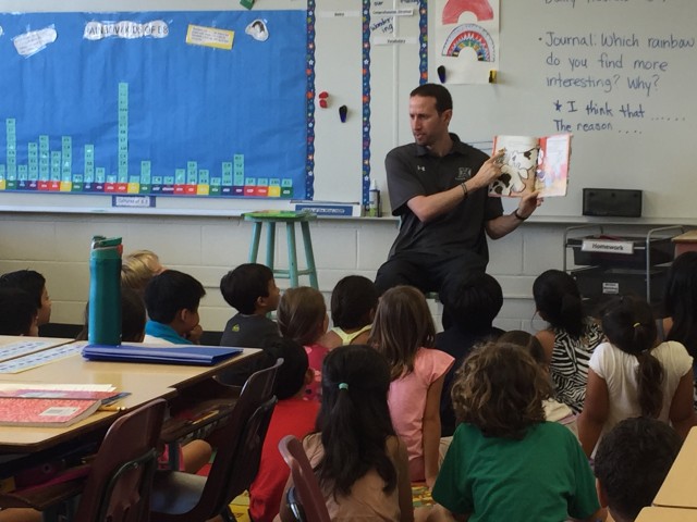 Head coach Eran Ganot read to children at Waikiki Elementary on Friday.